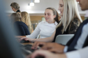 A small group of Longfield Academy students sit together whilst working on computers.