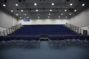 Photo of the main conference hall in Longfield Academy, featuring dark blue tiered seating.