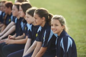 Students sitting in a line on a fields during a P.E. lesson