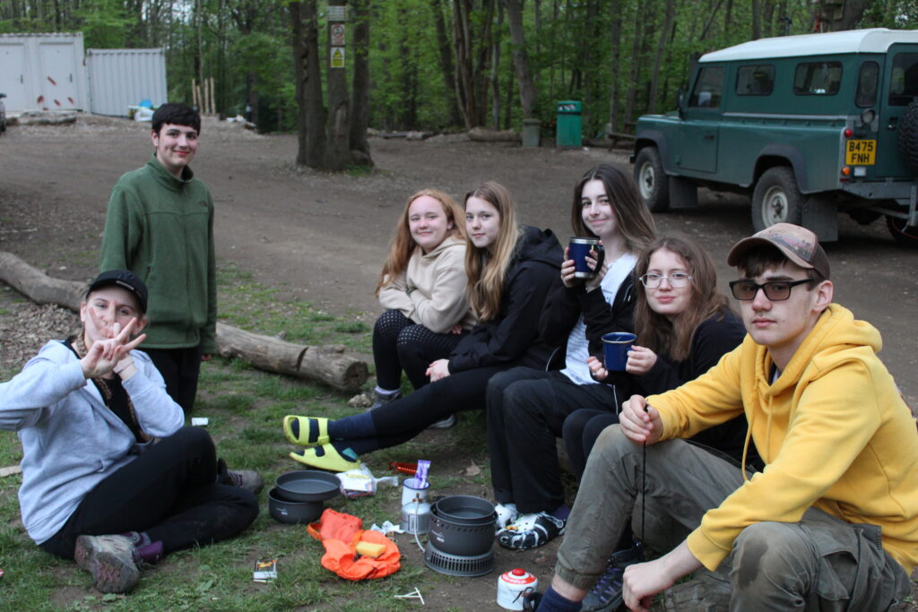 A group of students are pictured sitting outdoors, posing for the camera and drinking coffee.