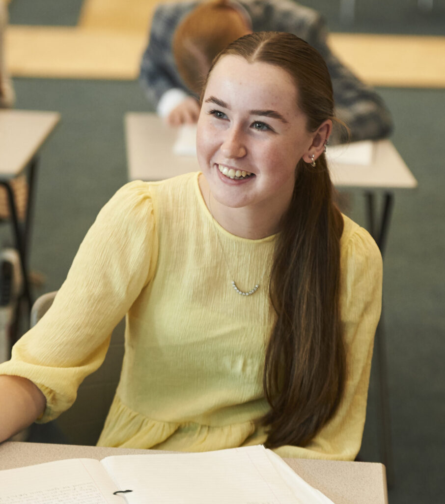 Student in a yellow shirt sat at a desk