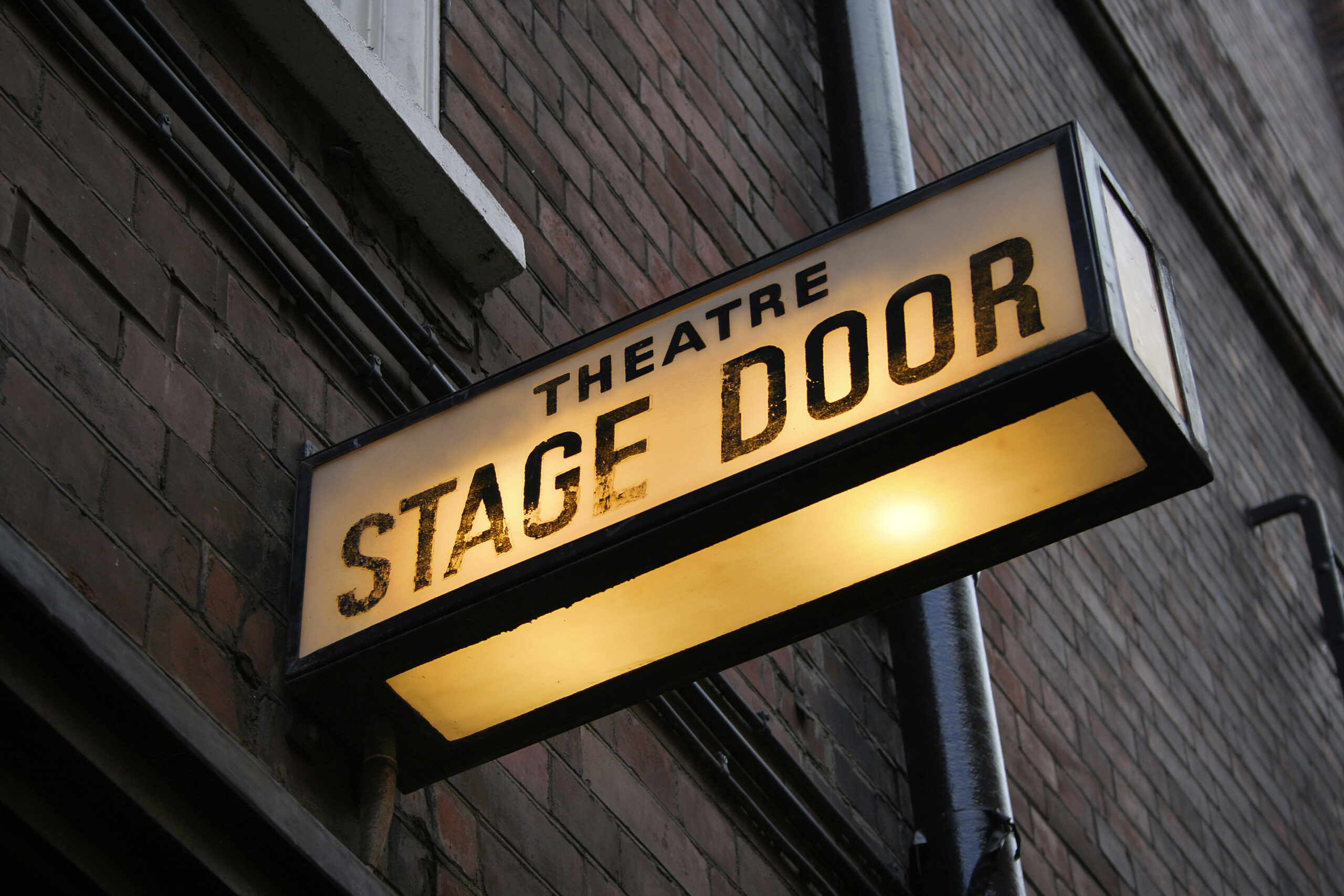 A glowing sign saying 'Theatre Stage Door'
