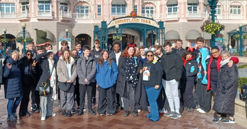 A group of students smiling for a photo in front of the Disneyland Paris entrance